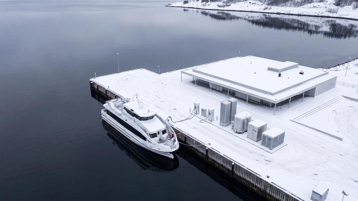 Hurtigbåt ved snødekt kai, koblet til ladere på kaia